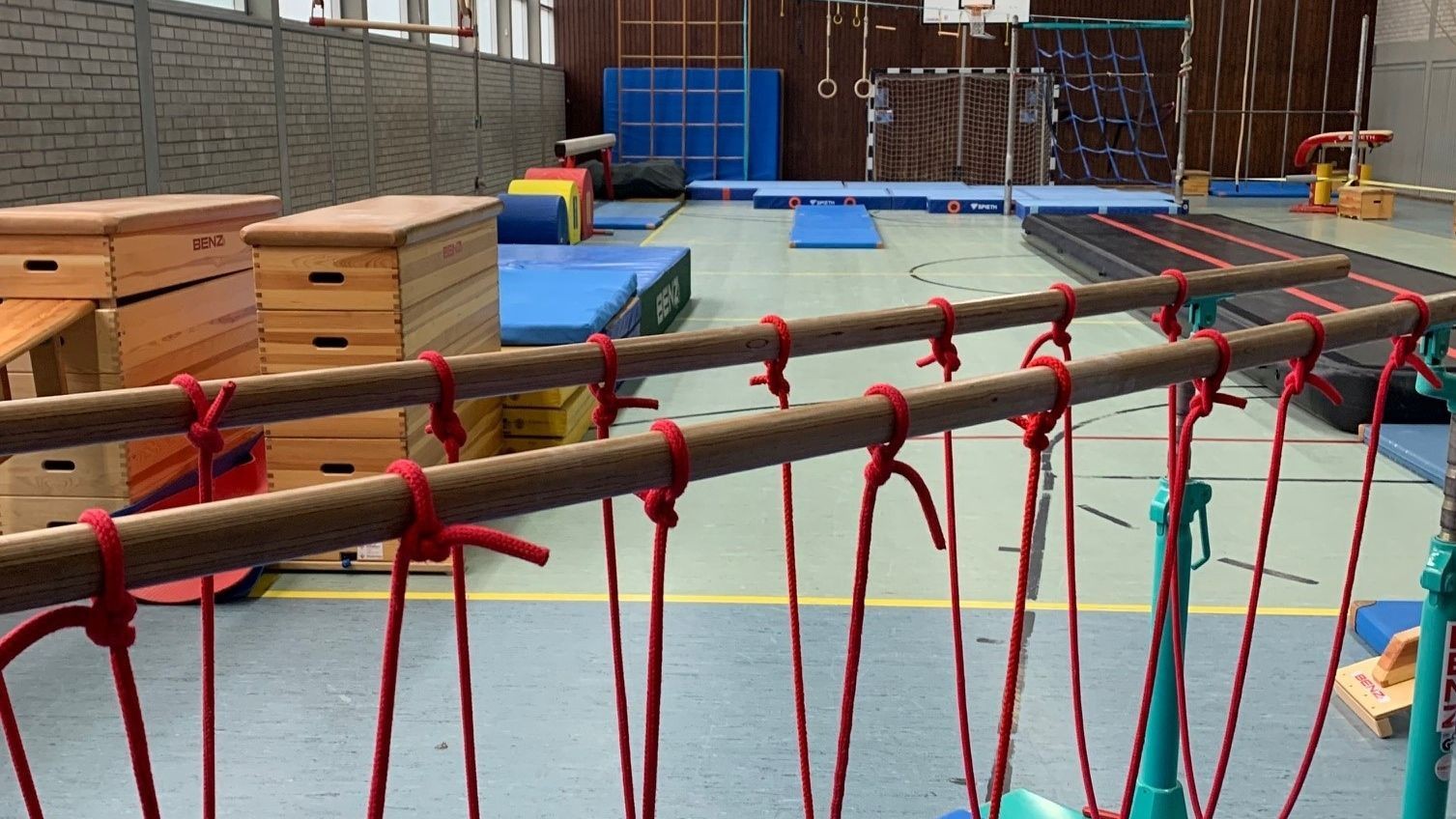 Indoor gym with gymnastics equipment, including balance beams and climbing ropes.