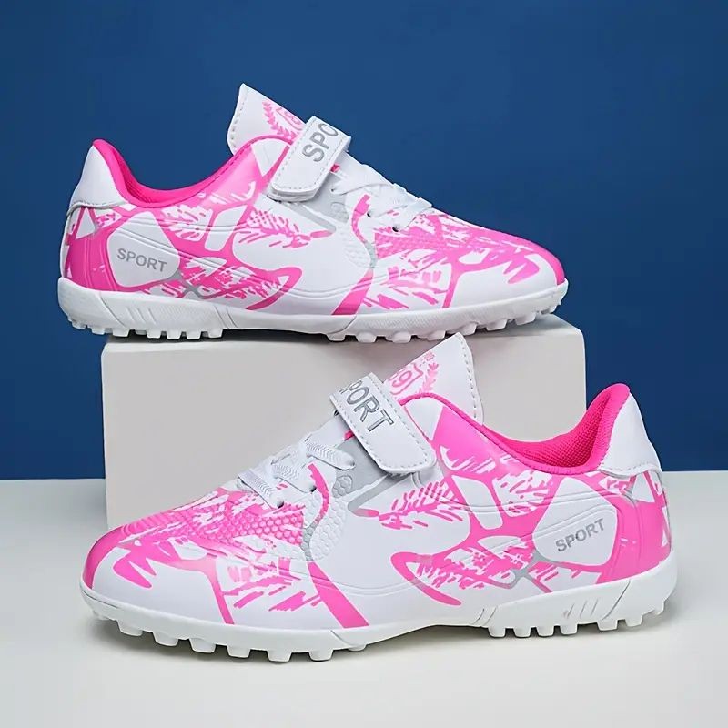 Pair of white and pink sports shoes with abstract patterns displayed on a white box.