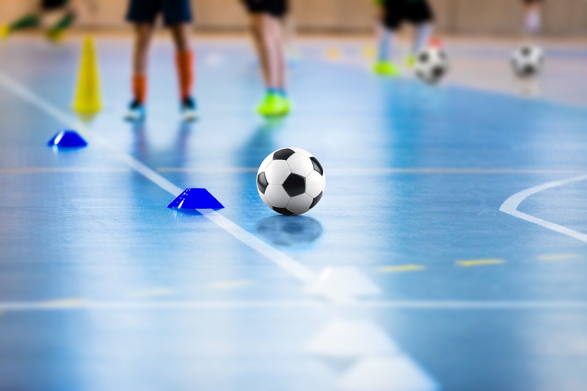 Futsal-Fußball-Trainingsplatz. Junge Sportler mit Bällen auf training. Nahaufnahme des Futsalballs. Futsal Junior Player auf Indoor Training. Fußball Winterklasse am School Indoor Futsal Court