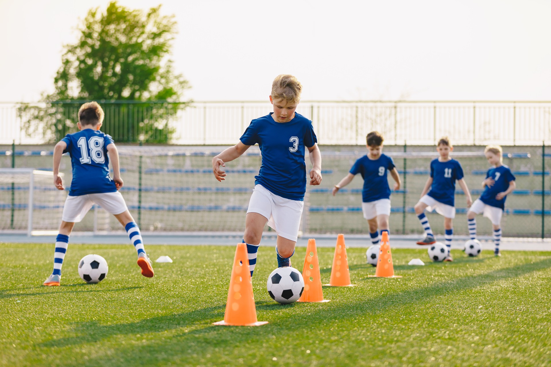 FußballTraining - Aufwärm- und Slalomübungen. Jungen üben europäischen Fußball auf dem Rasenschulfeld